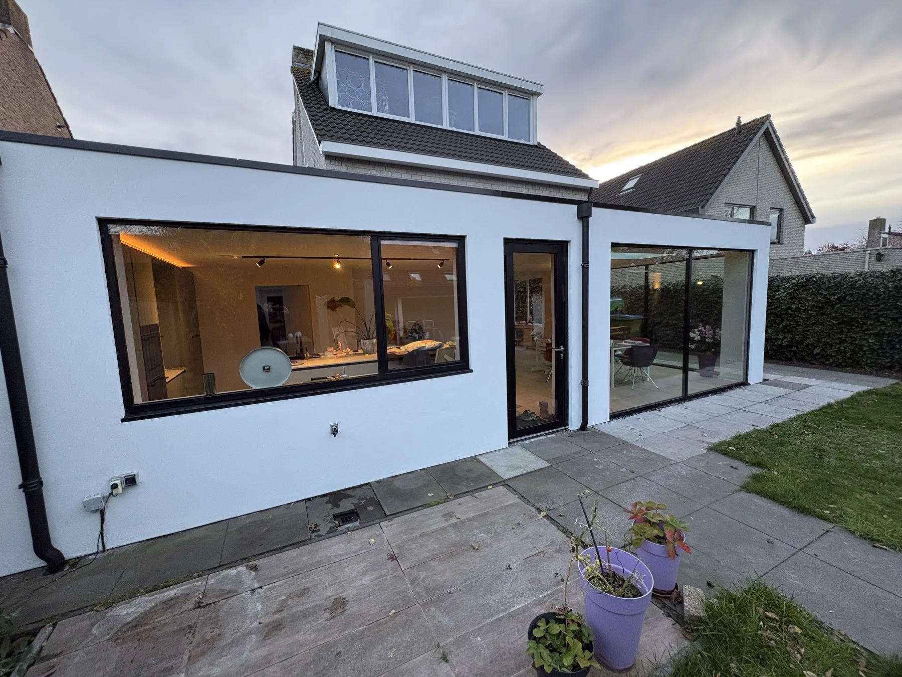 Glazen hoek in Bavel bij avondlicht met grote glaspartijen, gerealiseerd door Kozijn Gemak