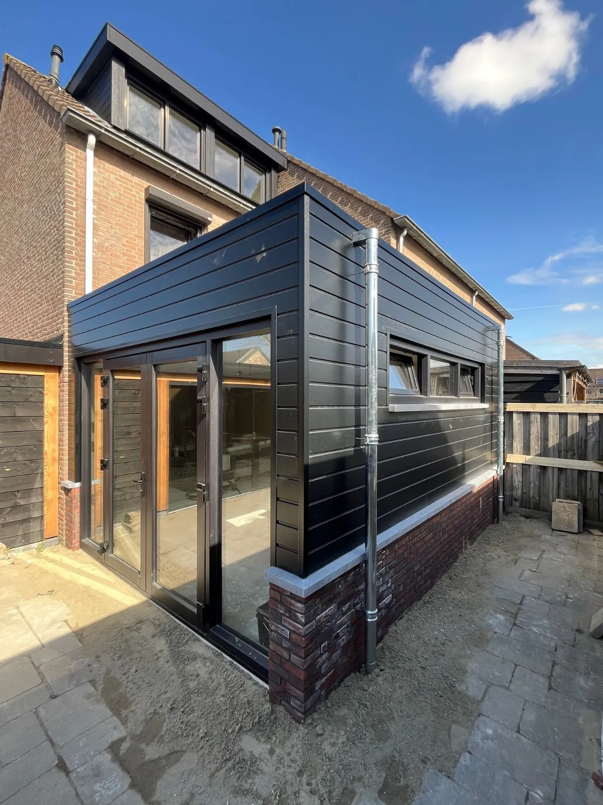 Aanbouw met zwarte gevelbekleding en zwarte kozijnen in Fijnaart