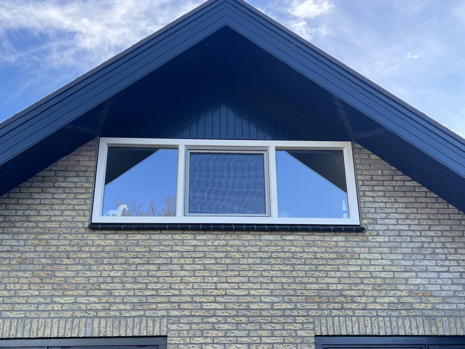 Kozijn in de kopgevel van een woning in Hoeven met donker zetwerk