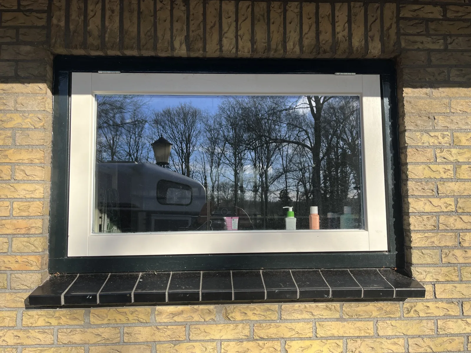 Wit raamkozijn in een gele gevel in Hoeven