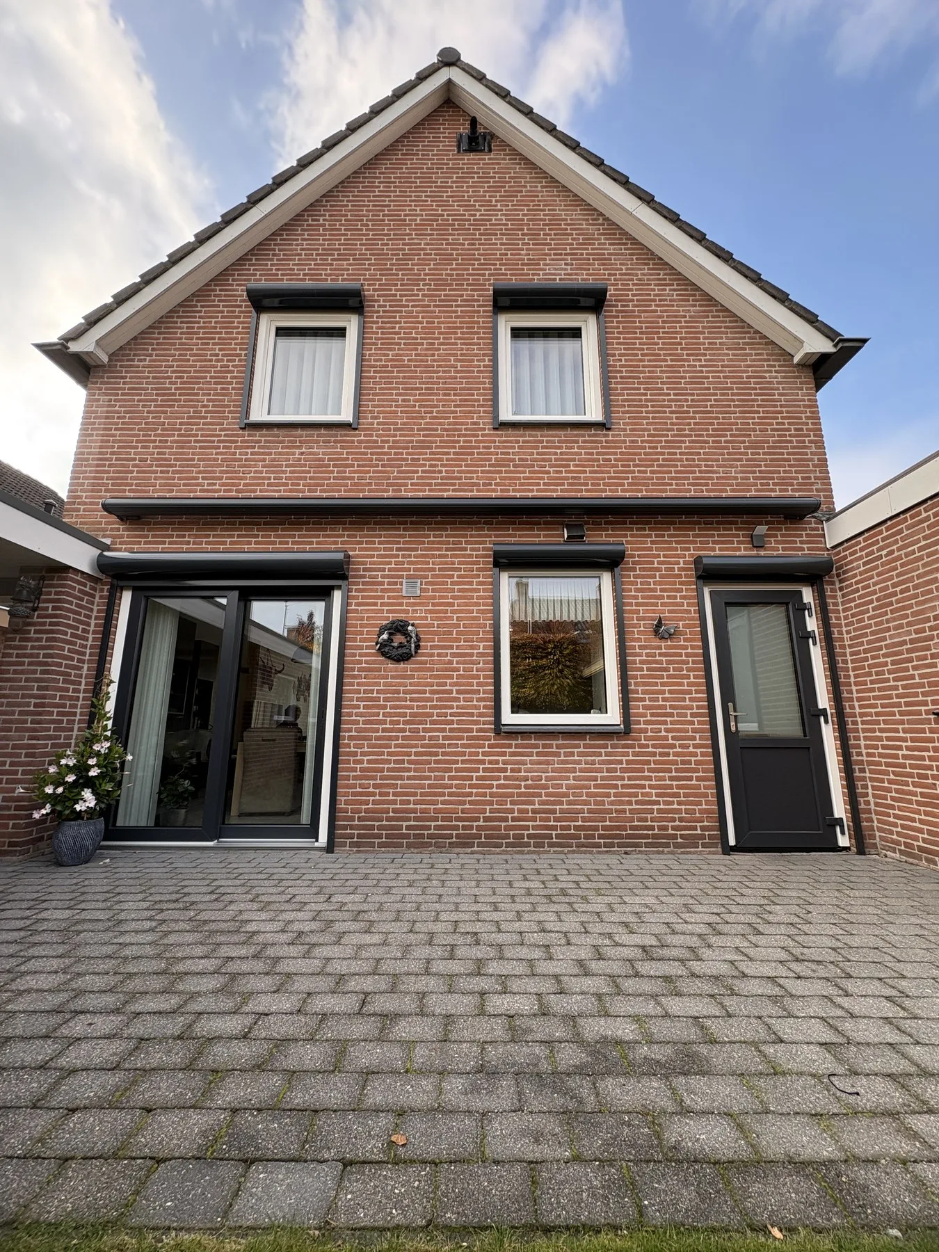 Voorgevel in Sprundel met witte kunststof kozijnen en een antracieten voordeur